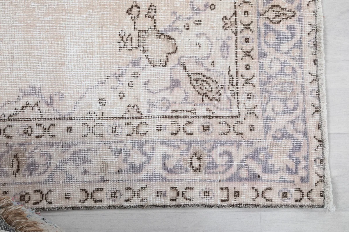 Detailed view of the rug's corner showing the border pattern and faded purple tones