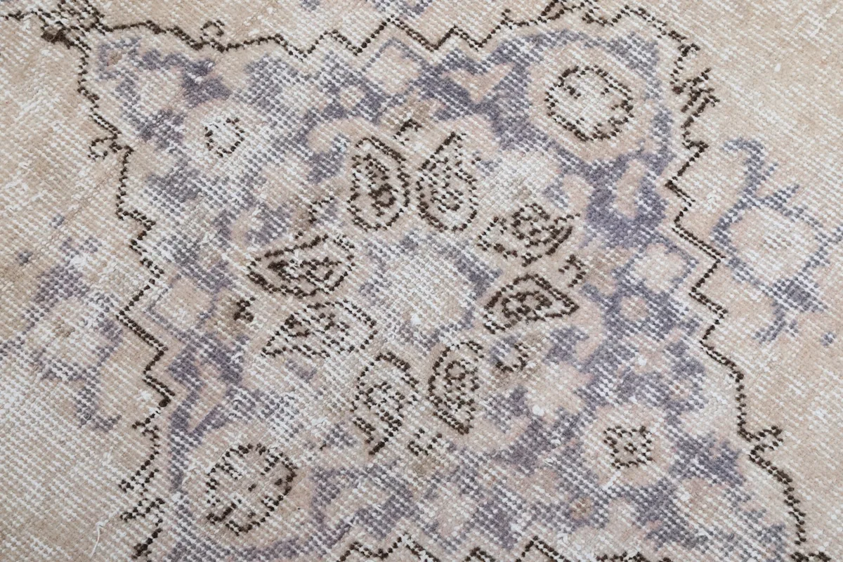 Detailed shot of the faded purple and gray colors within the rug's central medallion