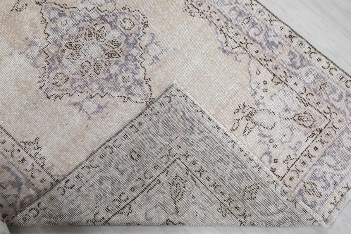 Corner of the rug folded back to show the cotton foundation and reverse side of the hand-knotted pile