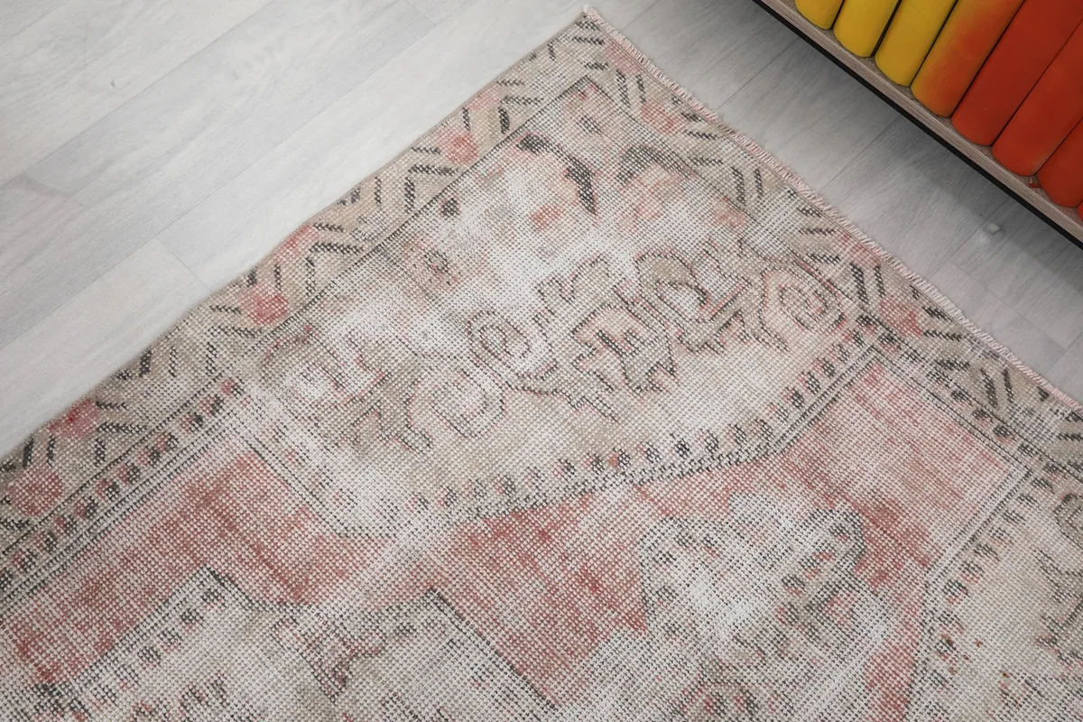 Corner detail of the rug, highlighting the faded geometric motifs and colors