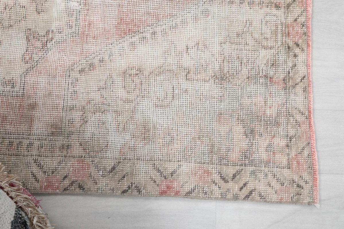 Detail of the faded rose and gray geometric border pattern on the rug
