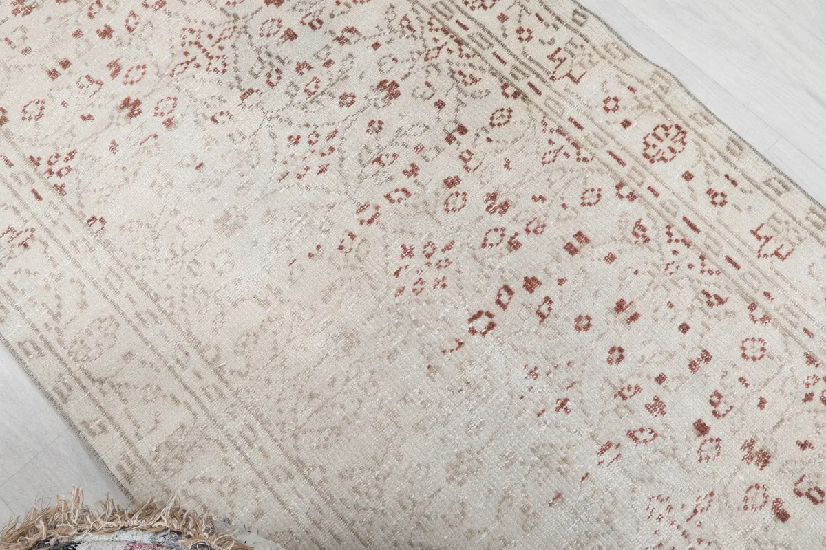 Diagonal view of the rug, showcasing the faded rust patterns and ivory background