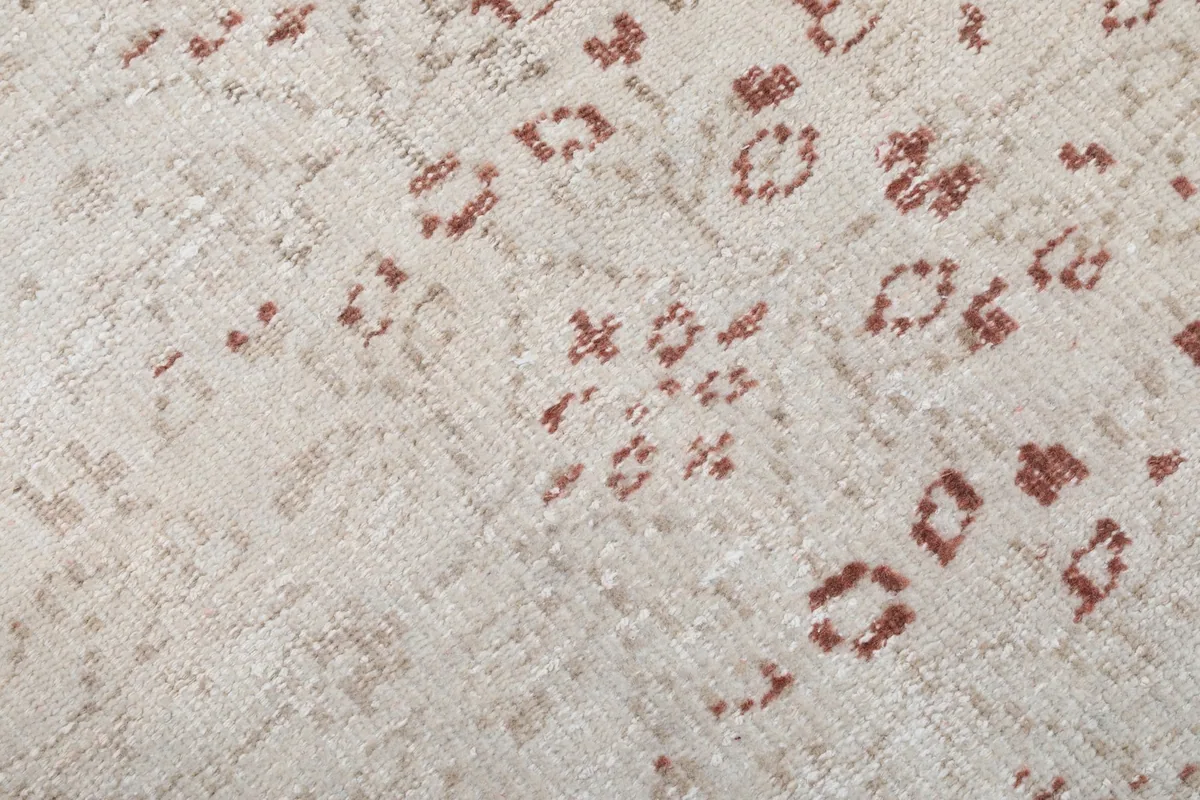 Close-up of the wool pile, showing the texture and muted rust colors of the motifs