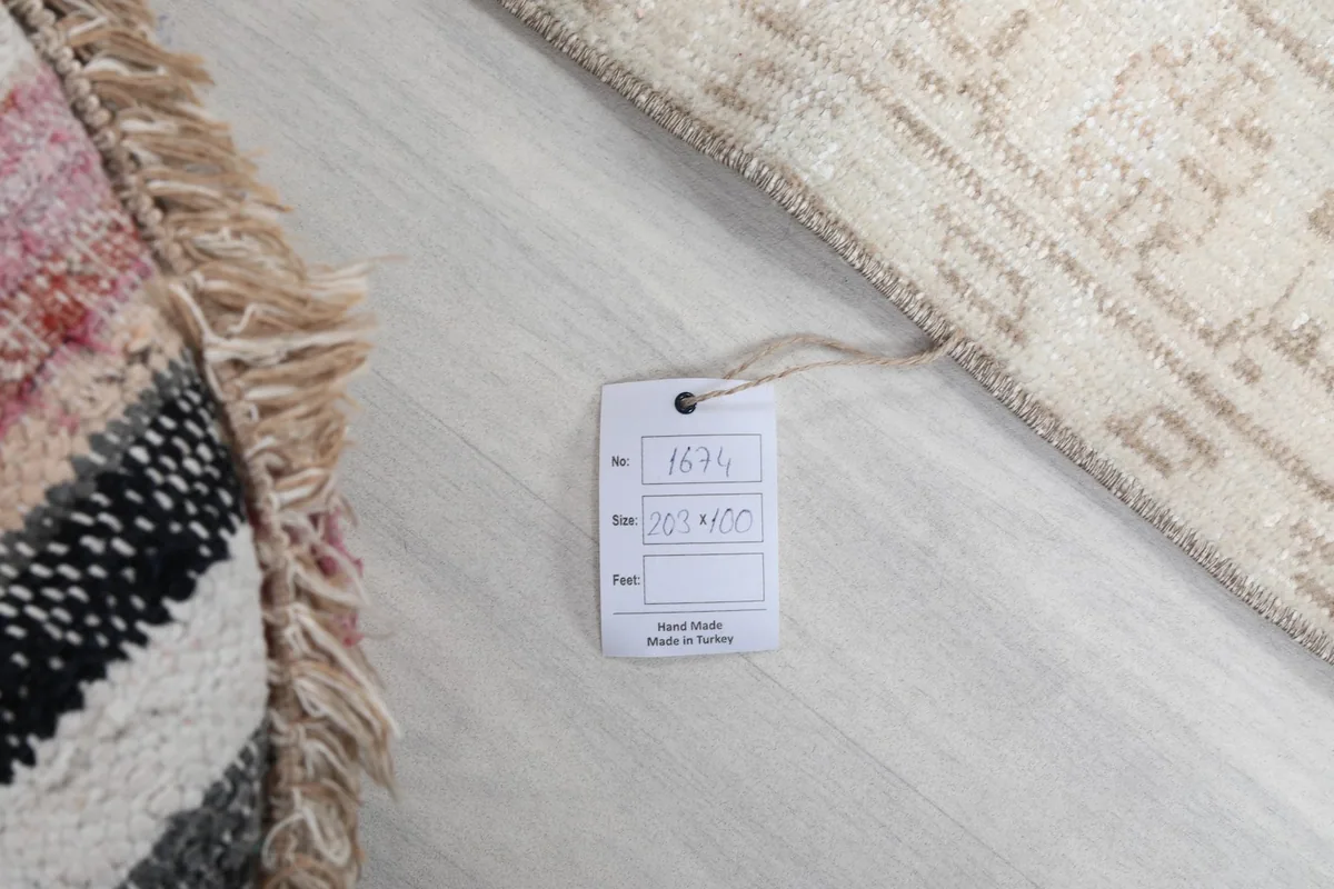Tag showing the rug's dimensions 100x203 cm and item number 1674, beside a colorful pouf