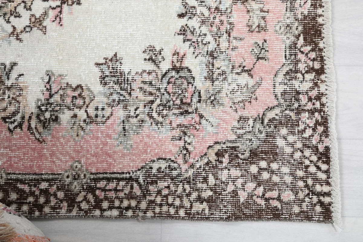 Detailed view of the corner border pattern and the soft rose and ivory colors of the rug