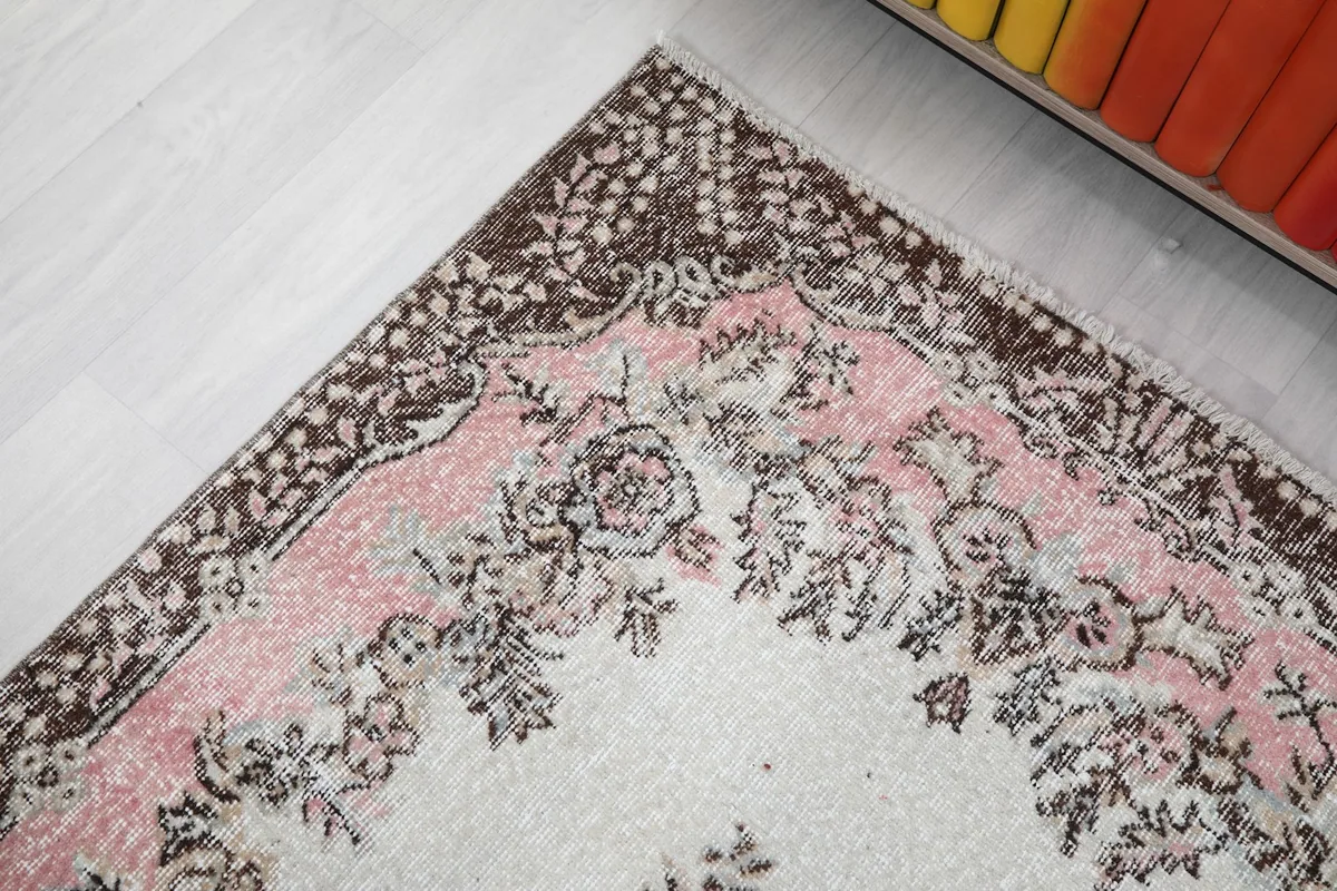 Detailed view of the rug's brown border with its repeating floral and geometric designs
