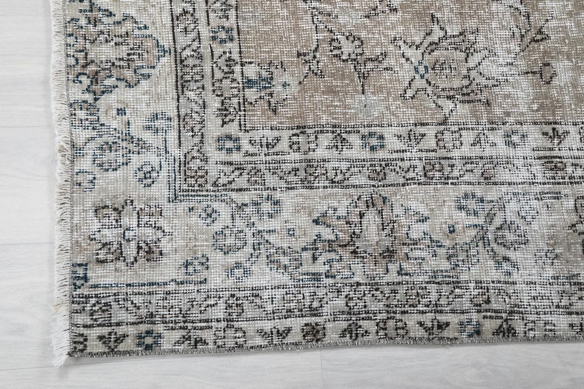 Close-up of the border and corner of the rug, showing gray and blue motifs