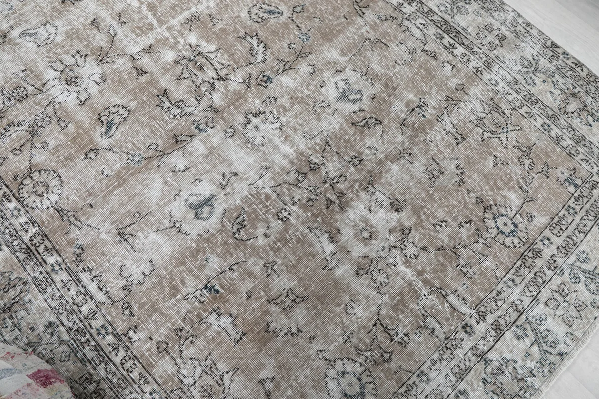 Overhead detail view of the rug's central field with faded floral designs