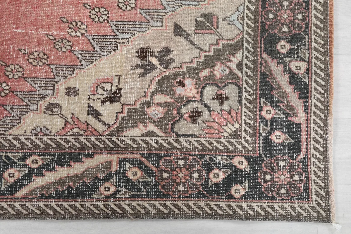 Close-up detail of the rug's corner, showing the geometric patterns and color variations in charcoal and beige