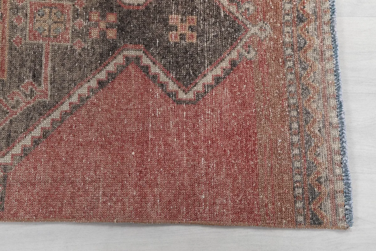 Detail of the rug's end, showing the rose field, subtle border, and hand-finished edge