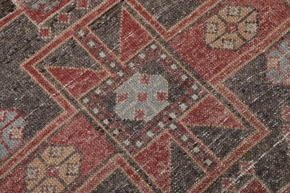 Close-up of the hand-knotted wool pile, revealing texture and color variations within the geometric design