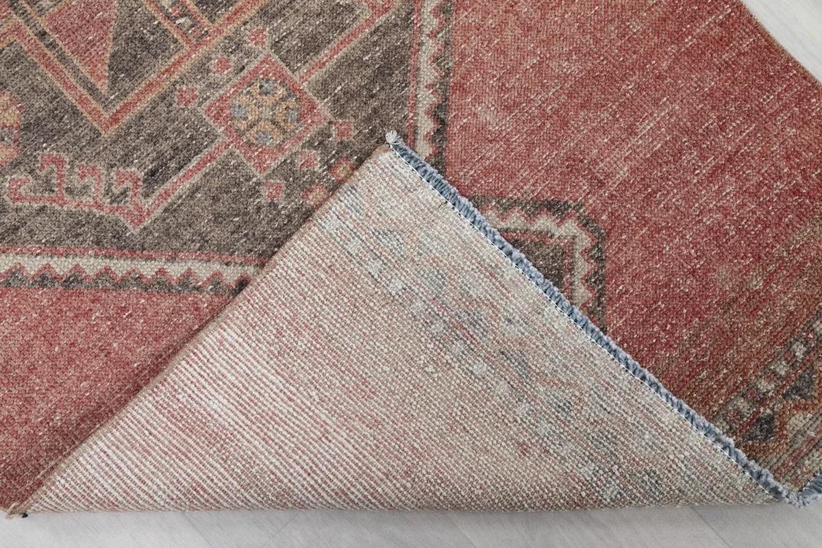 Corner of the rug folded back, showing the cotton foundation and hand-knotting on the reverse side