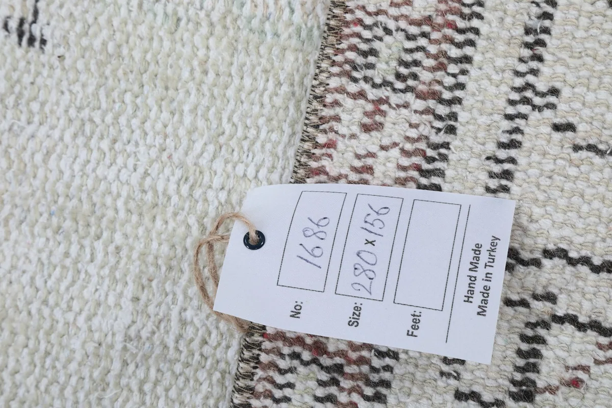 Close-up of the rug's back with a tag, indicating its handmade origin and size.
