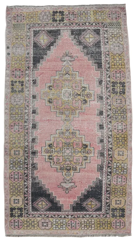 Full overhead view of the vintage pink and black geometric Anatolian rug on a white background