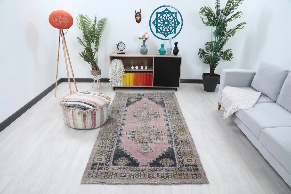 Vintage pink and black geometric rug displayed in a bright living room setting with modern furniture