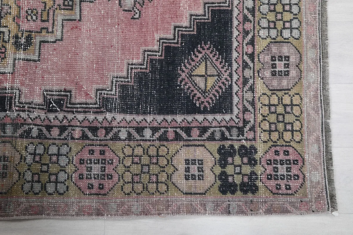 Detailed view of the rug's border pattern in gold, gray, and black tones