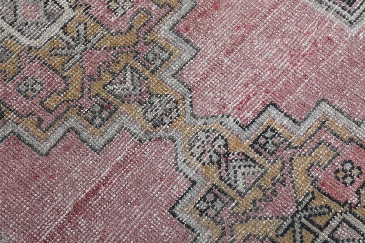 Close-up of the low wool pile texture and color variation in the pink and gold areas