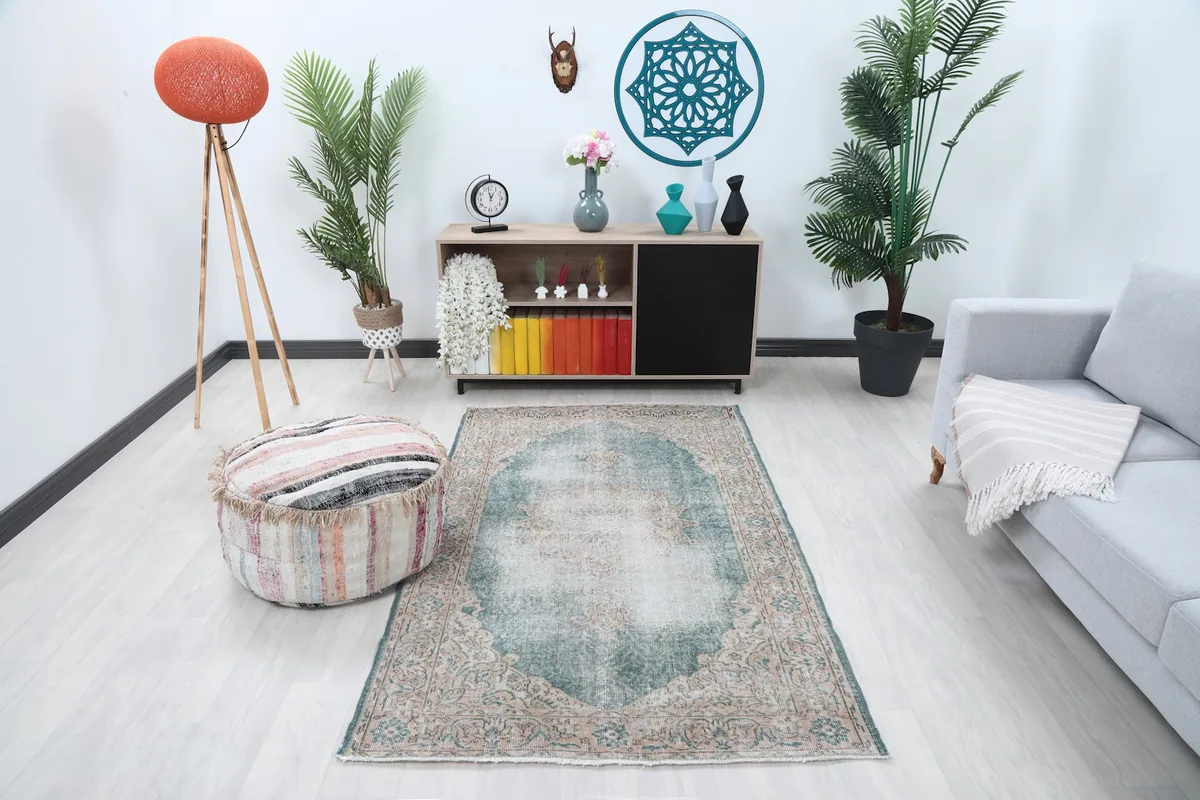 Vintage Anatolian rug in a living room setting with a gray sofa and pouf