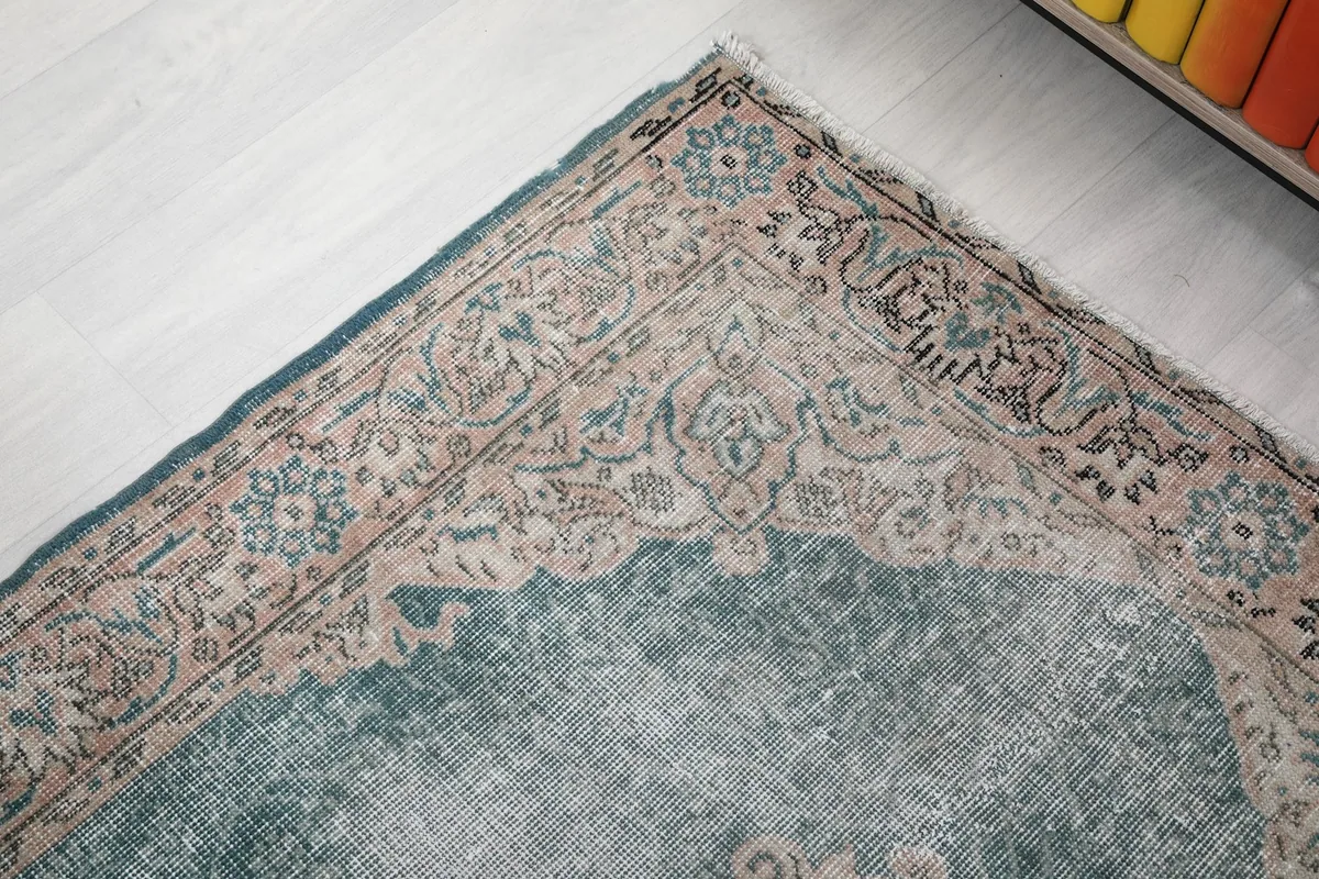 Detail of a rug corner with blue and rose floral motifs in the border