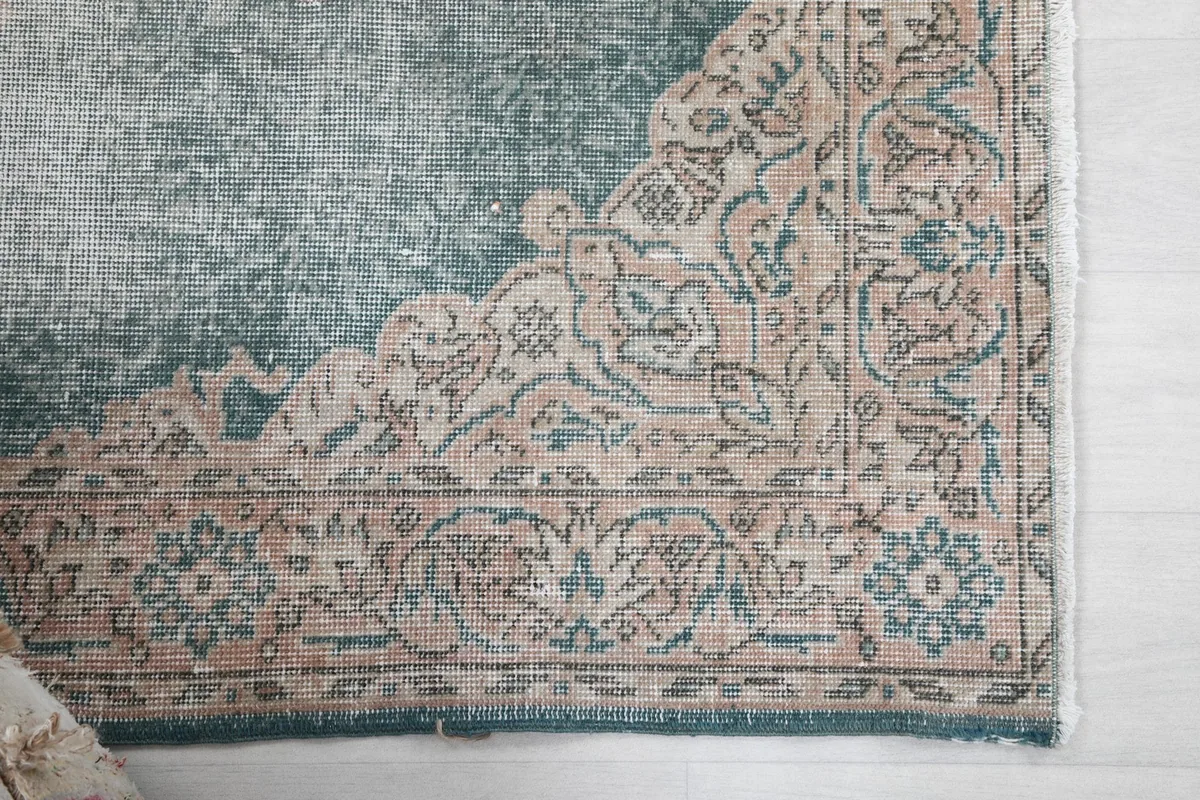 Detail of the rug's corner showing the rose and beige border pattern