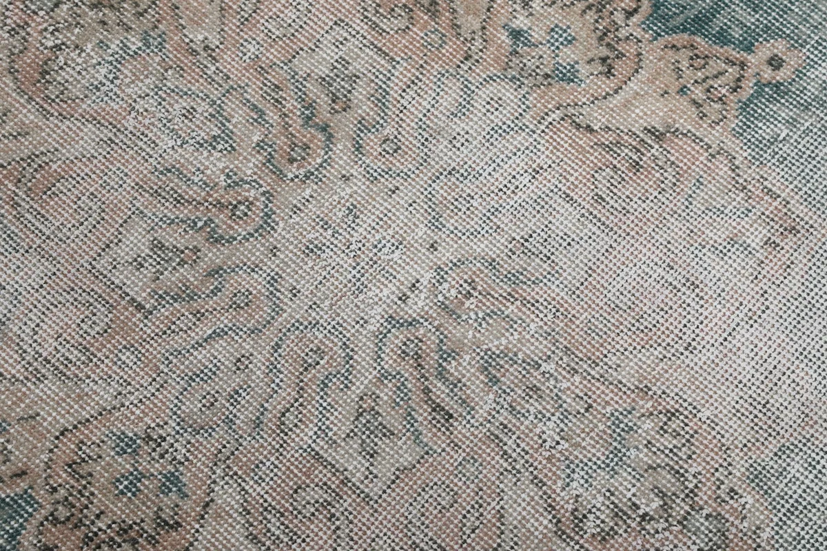Close-up of the low wool pile and intricate beige and rose patterns
