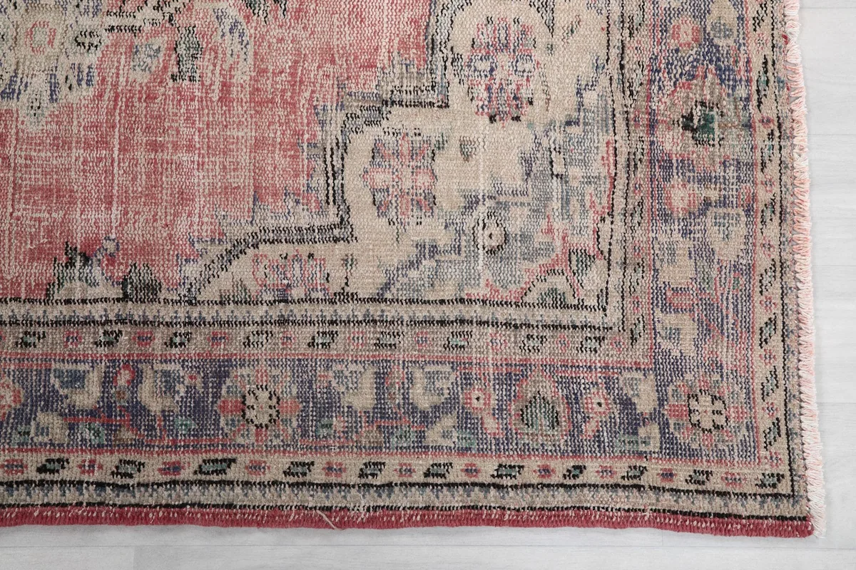 Detail of the rug's border with beige and blue patterns, showing natural wear