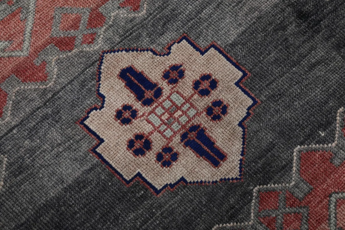 Macro detail of the hand-knotted weave within a beige and blue motif on the gray field
