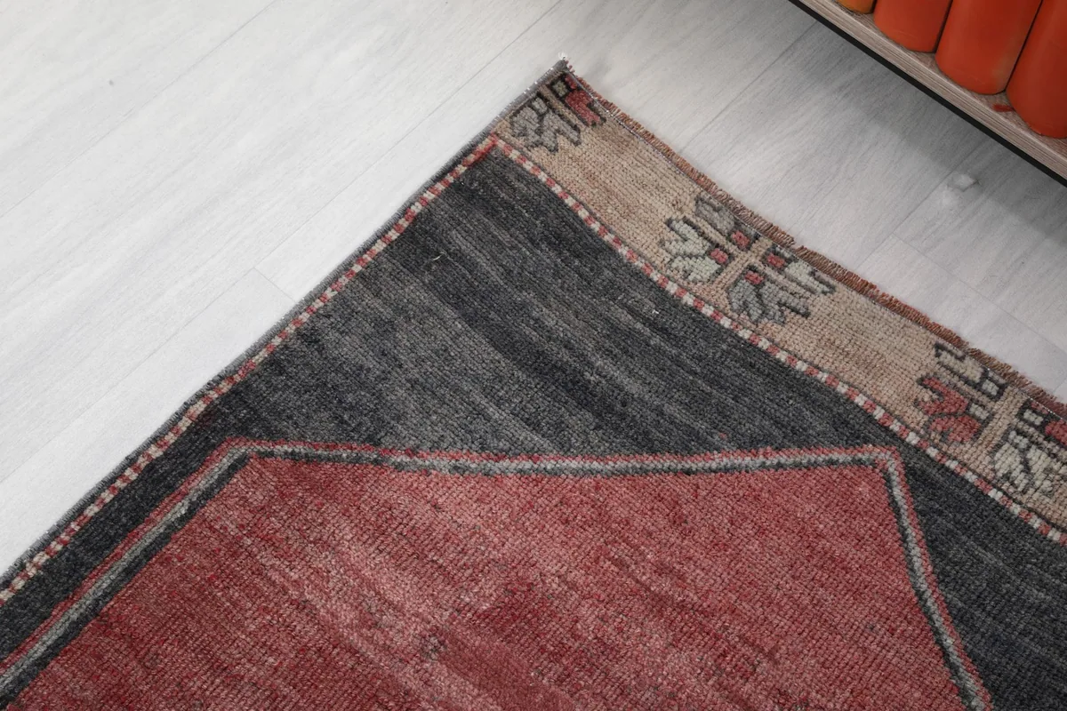Close-up of the rug's top corner, showcasing the gray border and beige patterned fringe