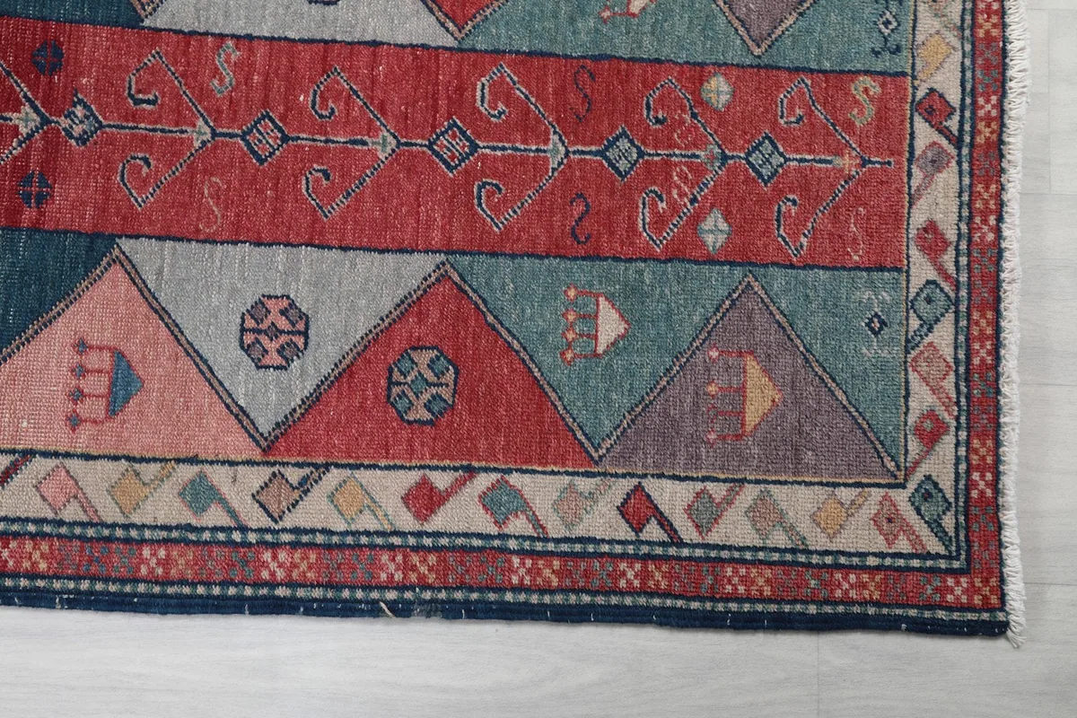 Detailed view of the rug's red central band and surrounding blue, pink, and beige geometric shapes