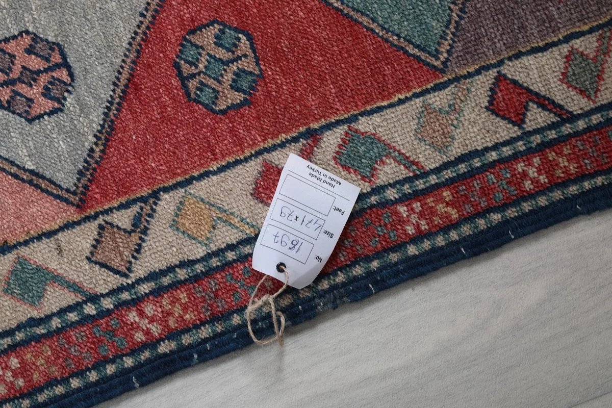 Close-up of the rug's reverse side, showing the hand-knotted backing and a product tag
