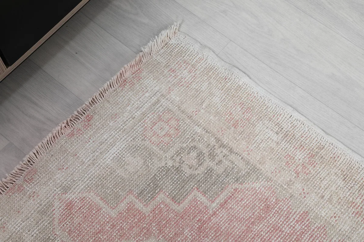 Corner detail of the rug, illustrating the border pattern and natural wear.