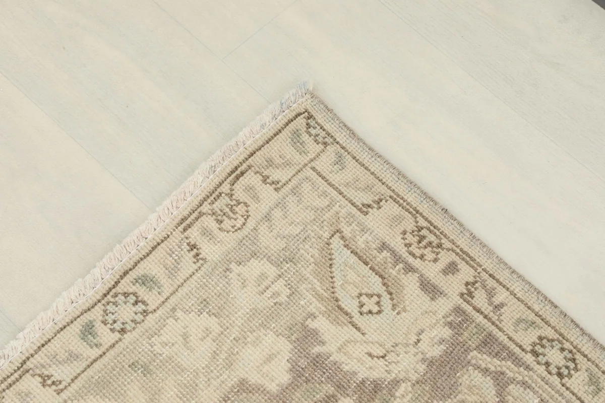 Overhead close-up of a corner of the rug, detailing the border design and the subtle color shifts in the pile.