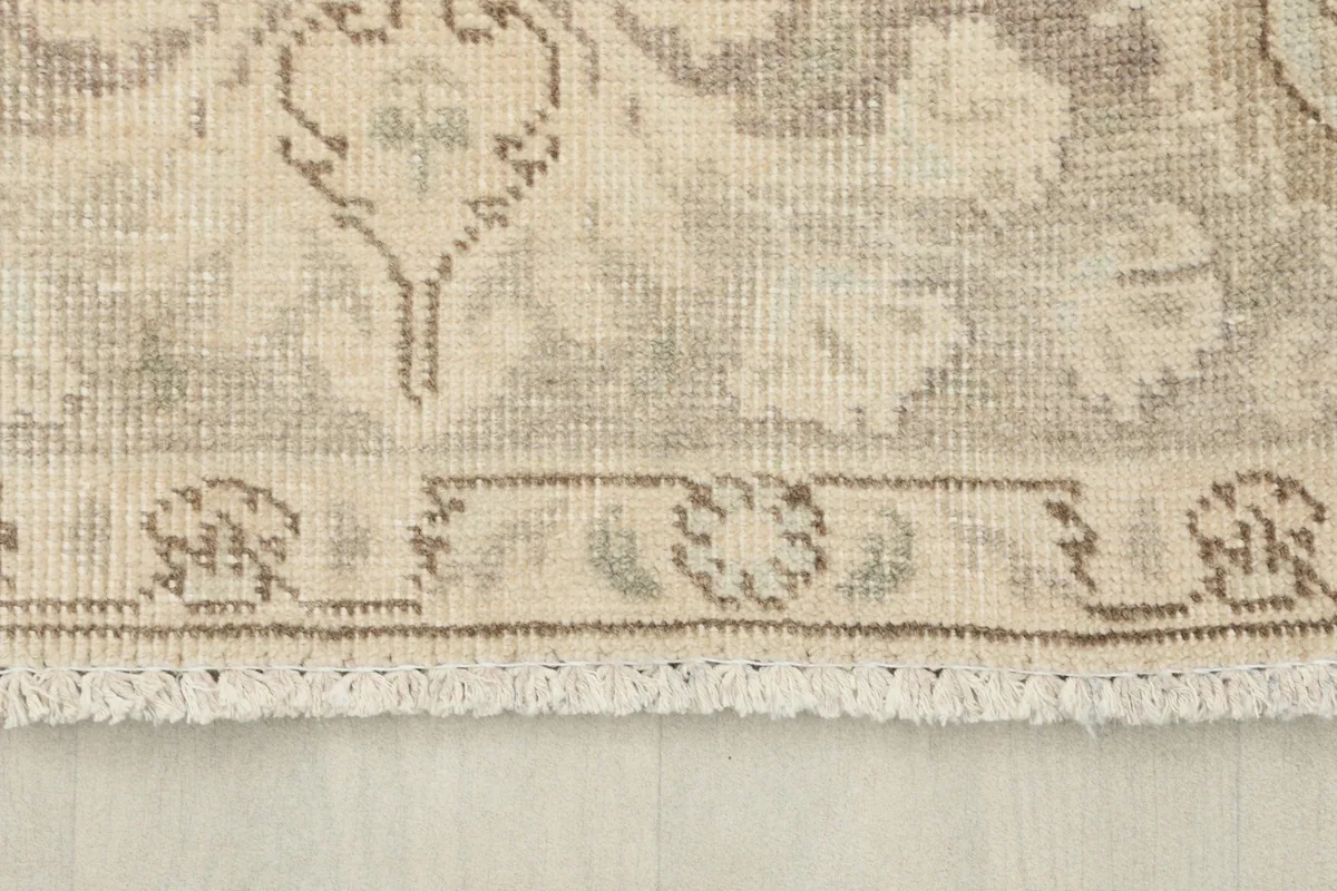 Detailed view of the rug's fringe and a section of the border, showing the natural wear consistent with vintage pieces.