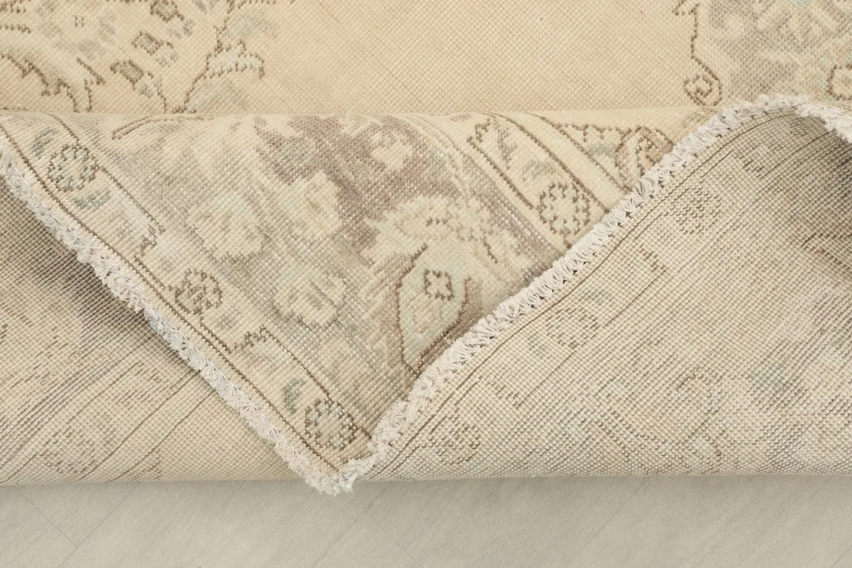 Corner of the rug folded back, showing the underside and the hand-knotted construction.
