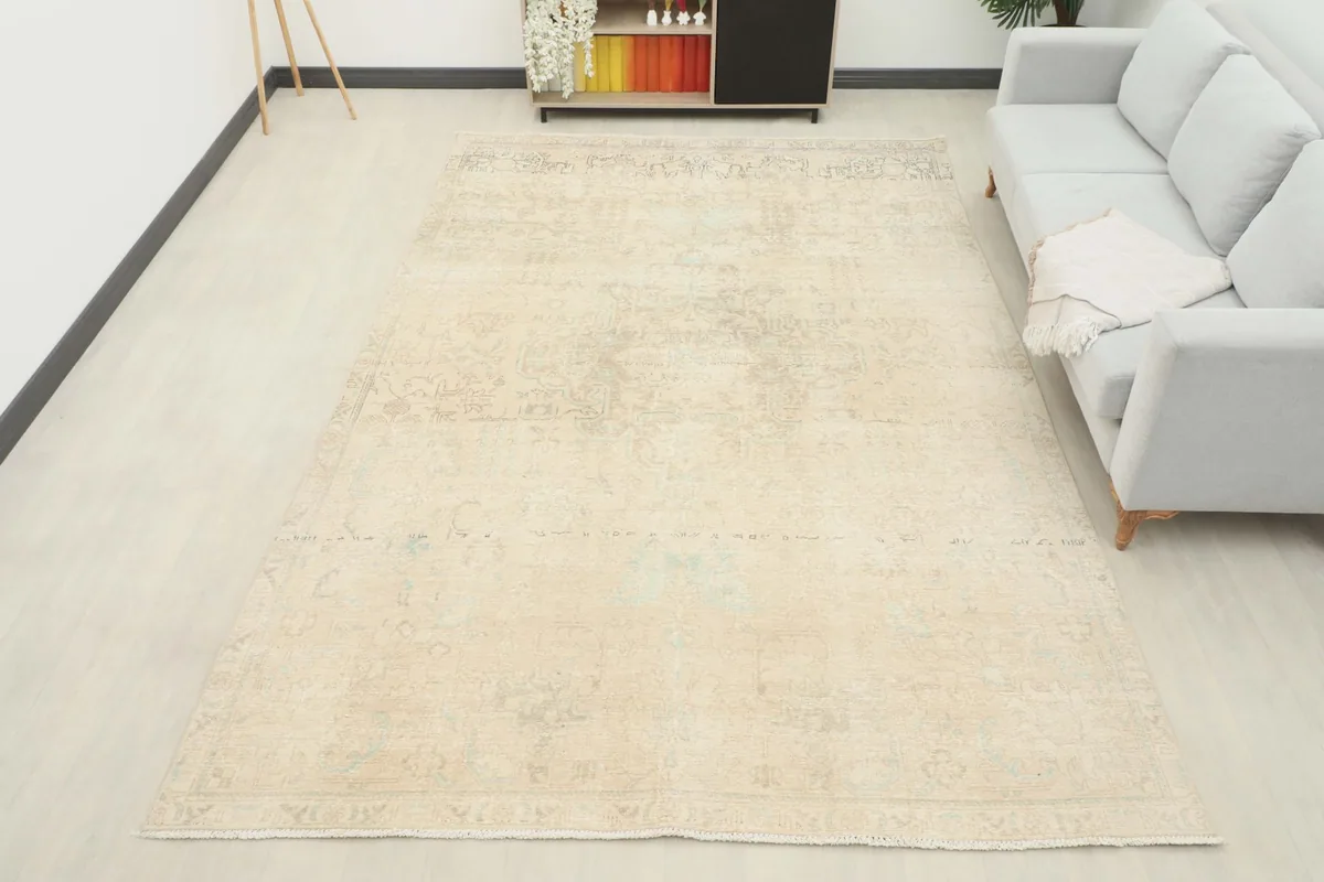 Overhead view of the large cream and gray vintage rug placed in a living room setting with a sofa