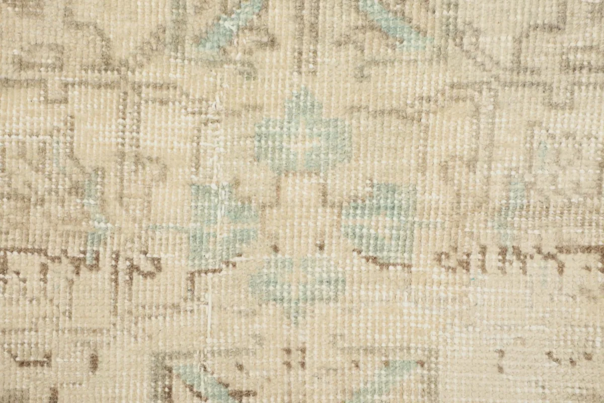 Close-up of the rug's surface, highlighting the low pile and subtle color variations in cream and blue