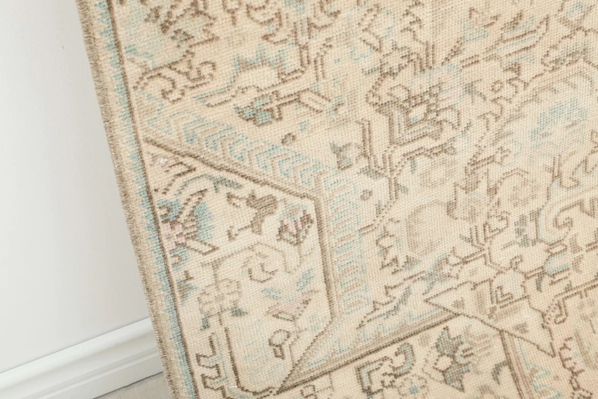 Close-up detail of the rug's edge, highlighting the beige, gray, and light blue geometric patterns