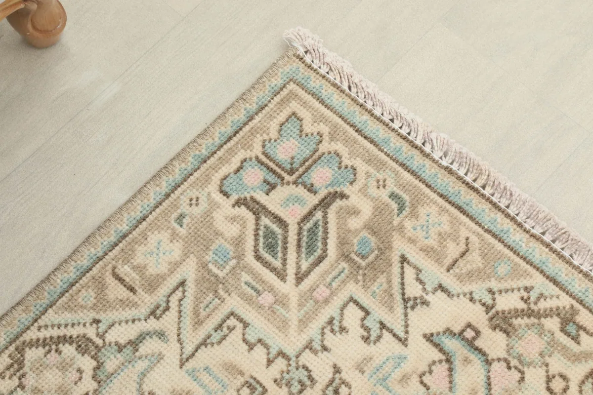 Corner detail of the rug, illustrating the border design with beige, tan, and blue geometric elements