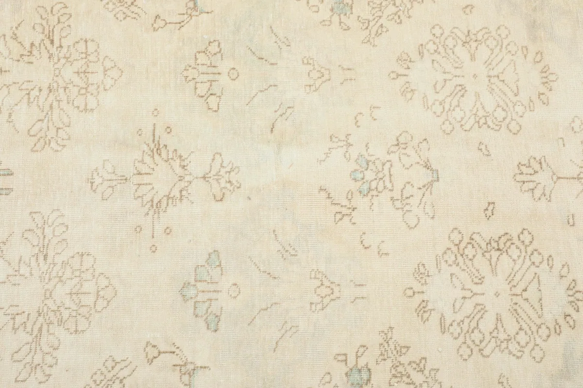 Close-up of the rug's texture and individual hand-knotted floral designs in tan and blue