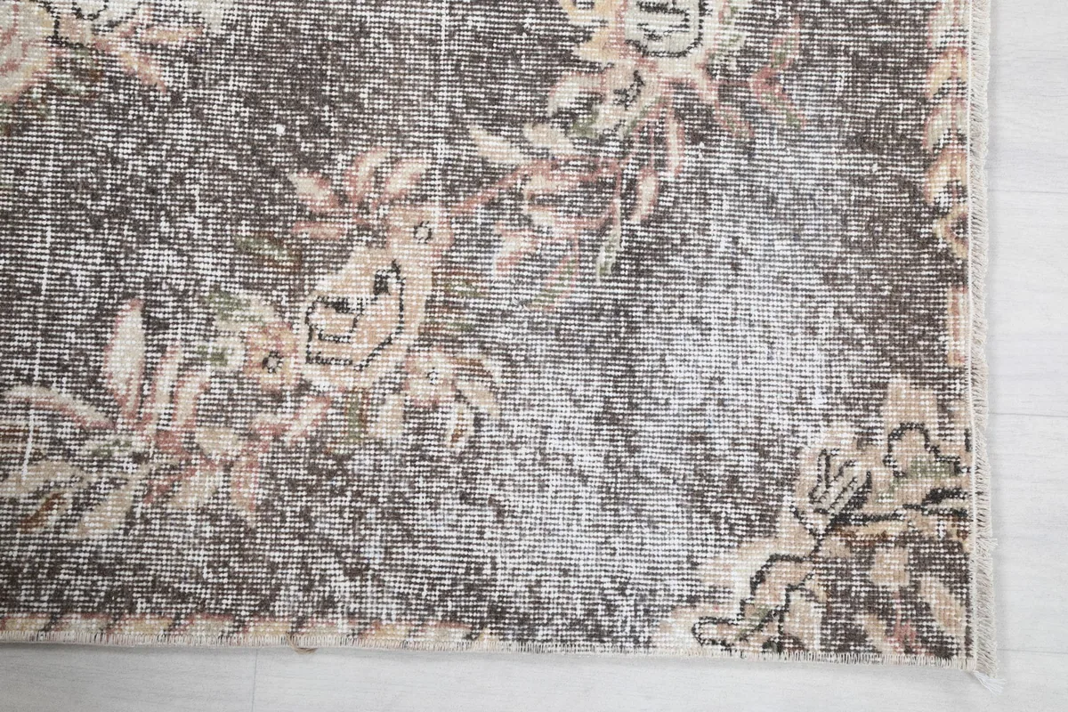 Detailed view of the rug's border and corner with floral motifs and subtle color variations