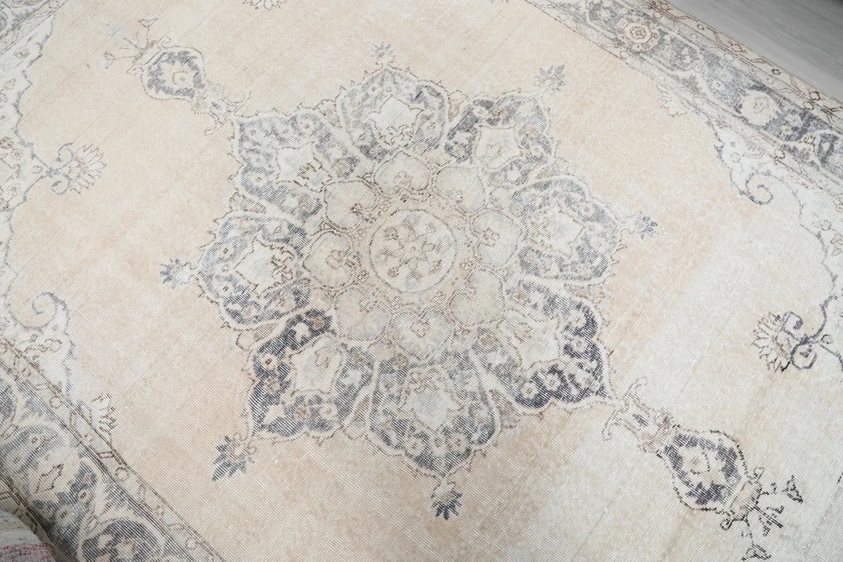 Detailed view of the intricate charcoal and gray medallion design on the ivory rug.
