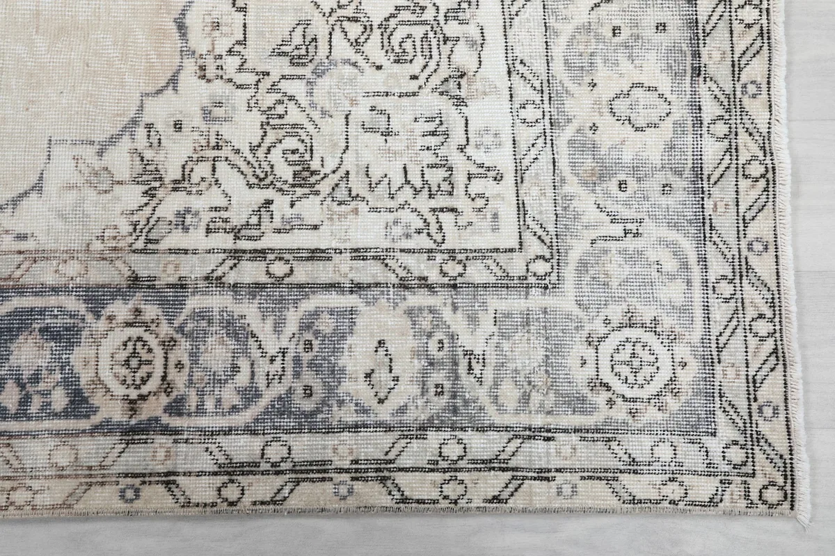 Close-up of the distressed charcoal and gray border patterns of the vintage rug.