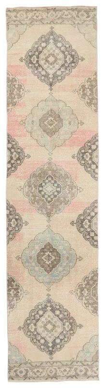 Full overhead view of the ivory, pink, and blue medallion vintage Anatolian runner rug on a white background.