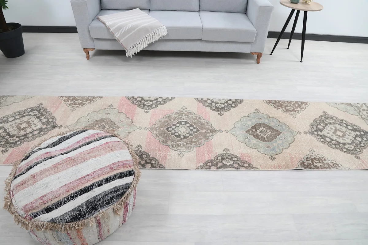 Full room view of the runner rug extending from an ottoman towards a sofa.