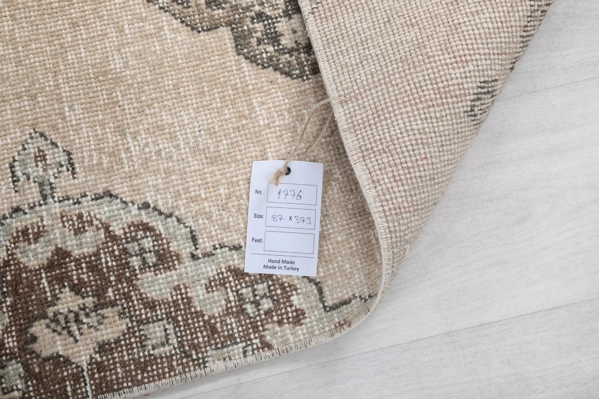 View of the rug's back with a tag, showing the hand-knotted wool on cotton foundation.
