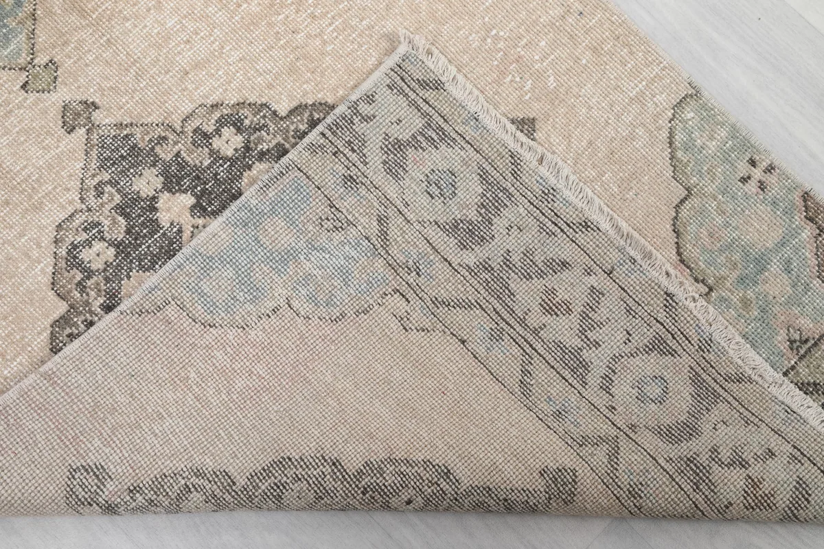 Corner of the rug folded back to show the cotton foundation and hand-knotted construction.