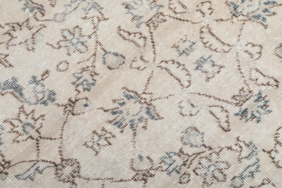 Close-up of the hand-knotted wool pile showing individual floral motifs in blue and brown