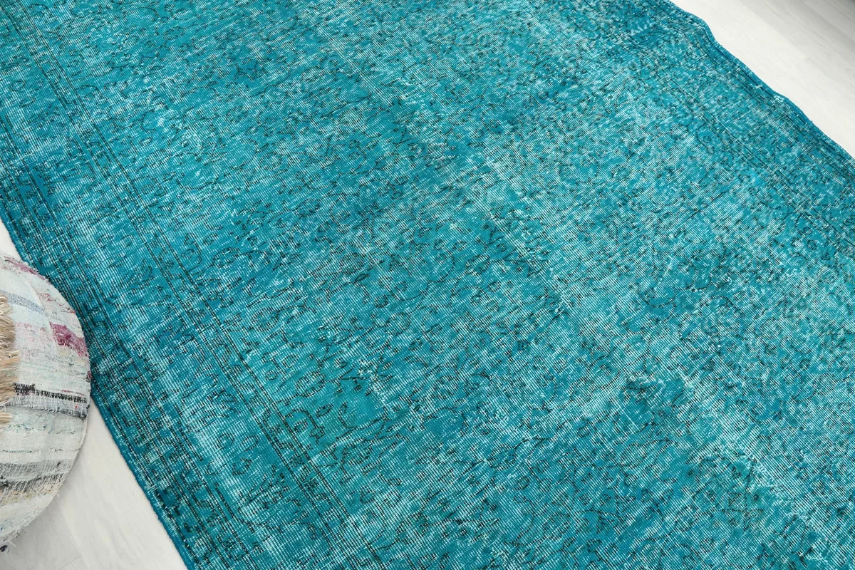 Angled view of the rug from another corner, showing the overall faded blue tones