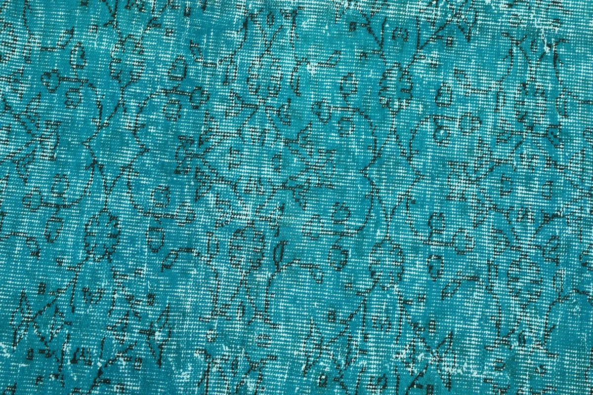 Macro view of the rug's pile, revealing the hand-knotted texture and faded geometric motifs