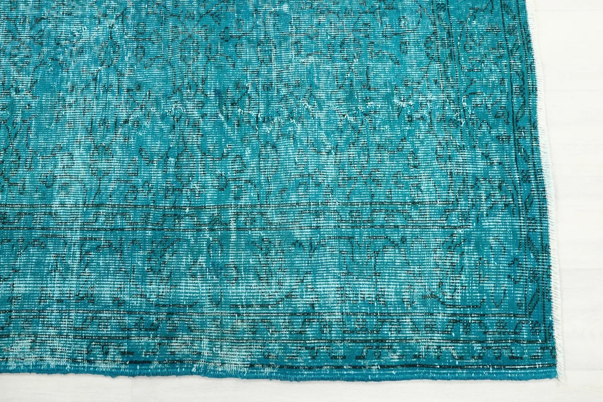 Detail of the rug's edge, showing the subtle border pattern and distressed areas